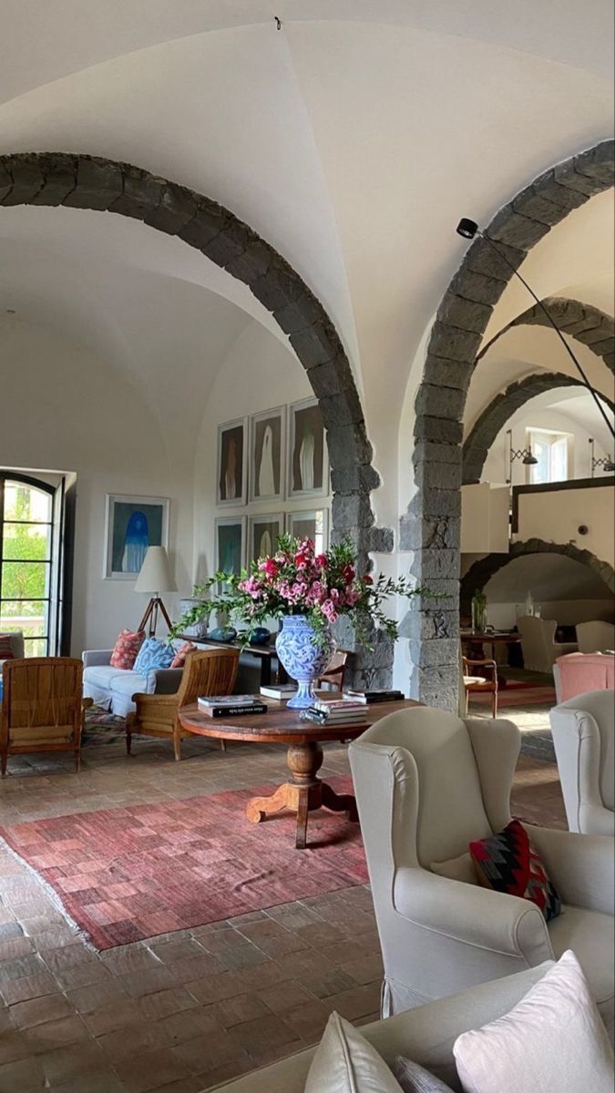 a living room filled with white furniture and lots of arched doorway leading to an open floor plan