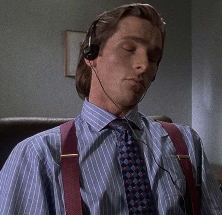 a man wearing suspenders and a tie with headphones on his ears looking down