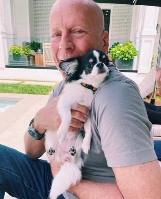 an older man holding a small dog in his lap while sitting next to a pool