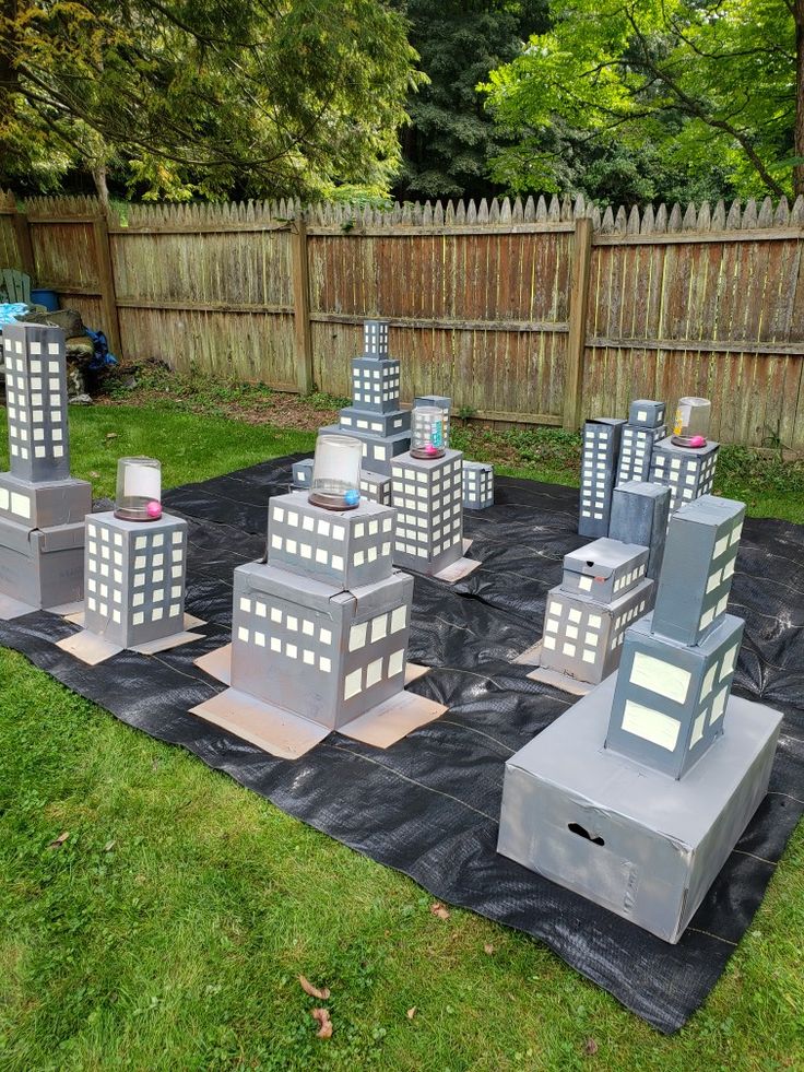 a group of buildings sitting on top of a black tarp in front of a fence