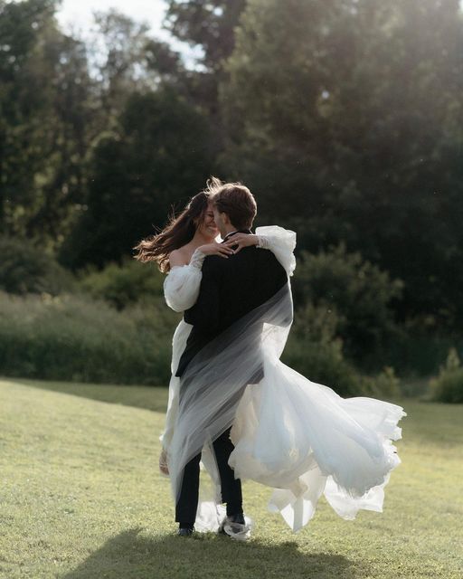 a bride and groom are hugging in the grass