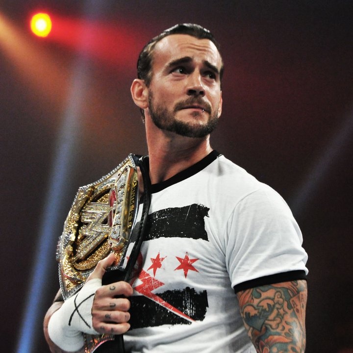 a man holding a wrestling belt on top of his chest and wearing a white shirt