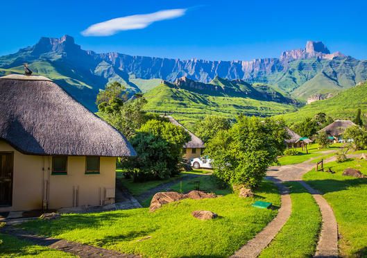 the mountains are in the distance with houses on each side and small huts at the bottom