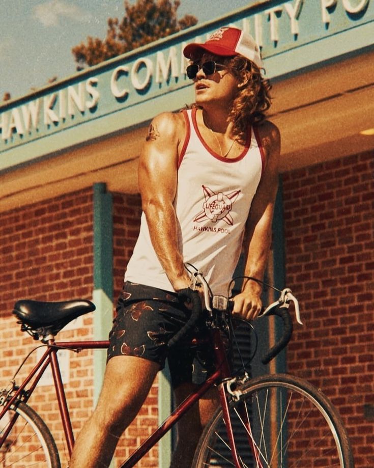 a man riding on the back of a red bike in front of a brick building