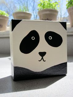 a panda face painted on the side of a box with potted plants in the background