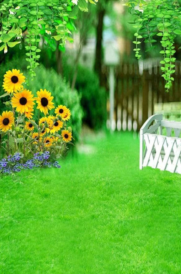 a white bench sitting in the middle of a lush green yard with sunflowers