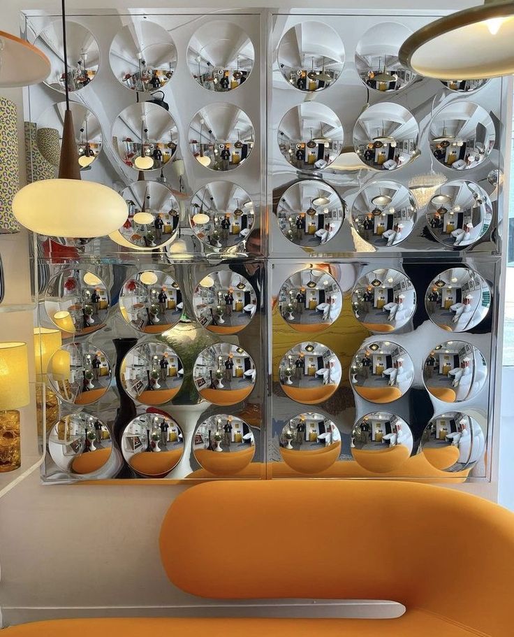 an orange chair sitting in front of a mirror wall