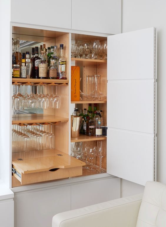 an open cabinet filled with wine glasses and bottles