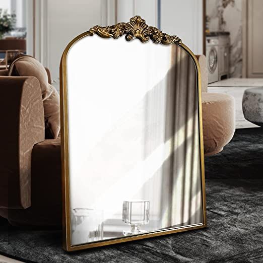 a large mirror sitting on top of a table next to a brown chair and ottoman