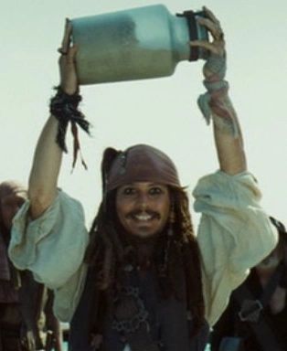 a man with dreadlocks is holding up a can in the air and smiling