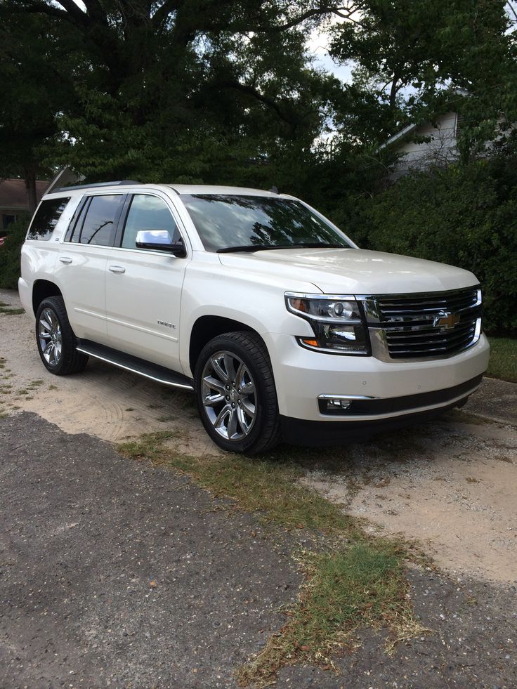 a white suv is parked in front of some trees