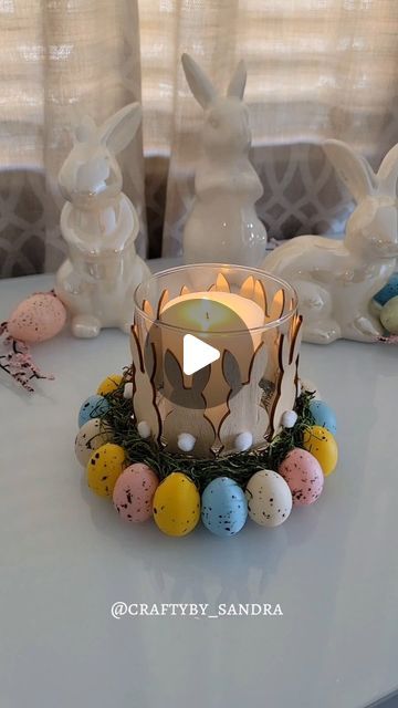 a candle that is sitting on a table with eggs around it and some bunny figurines in the background