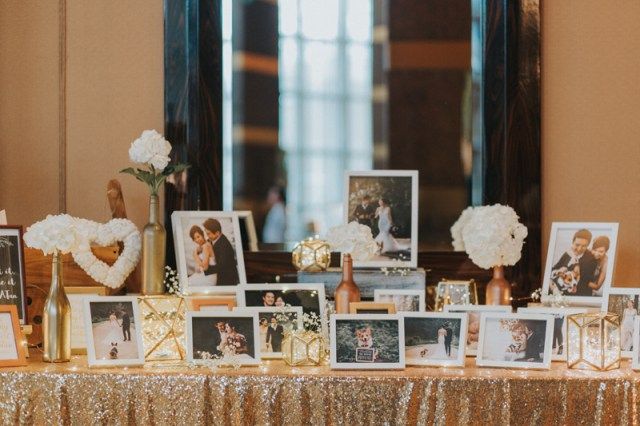 a table topped with pictures and flowers next to a window filled with gold sequins