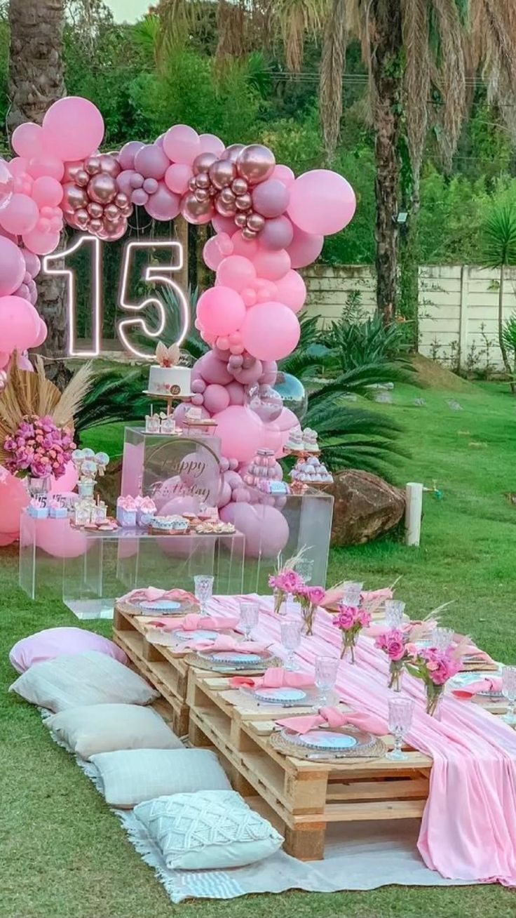 a table set up with pink balloons and decorations for a 21st birthday party in the backyard