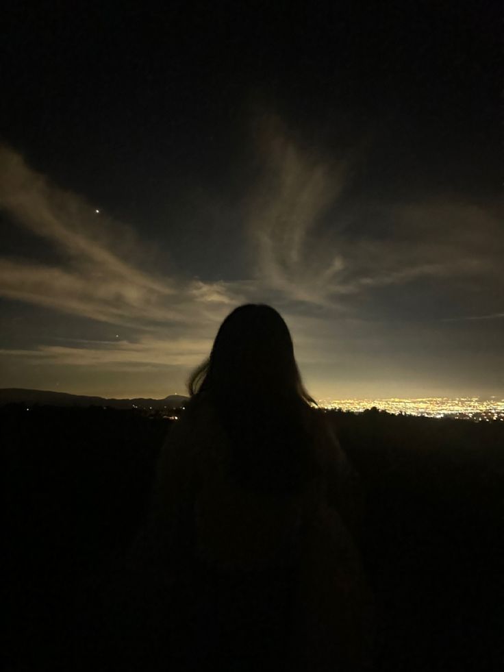 a woman standing on top of a hill at night