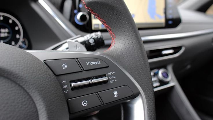 the interior of a car with an electronic device in the center console and steering wheel controls