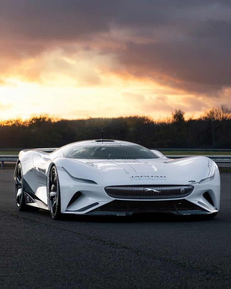 a white sports car driving on a race track at sunset or sunrise with dark clouds in the background