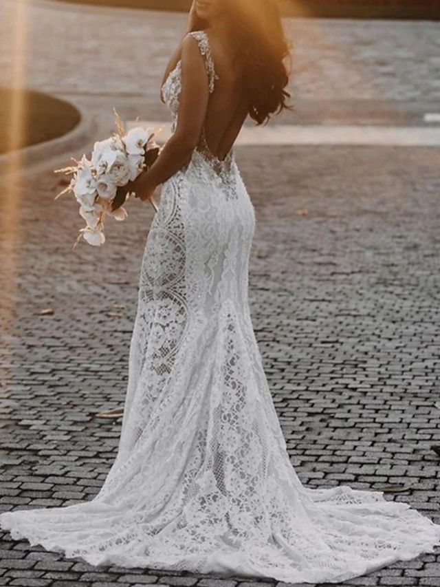 a woman in a wedding dress is standing on a cobblestone road with her back to the camera