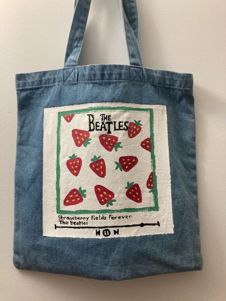 a blue bag with strawberries on it hanging from a hook in a wall next to a white wall