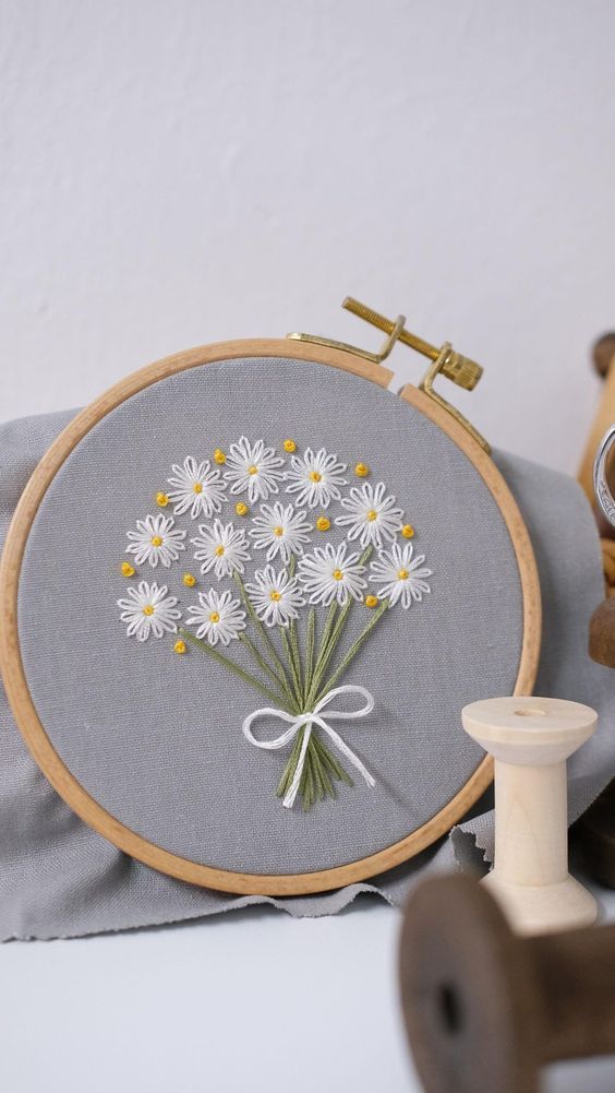 a close up of a embroidery on a table with a sewing needle and some other items