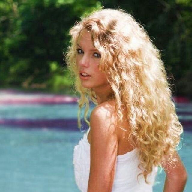 a woman with long blonde hair standing in front of water