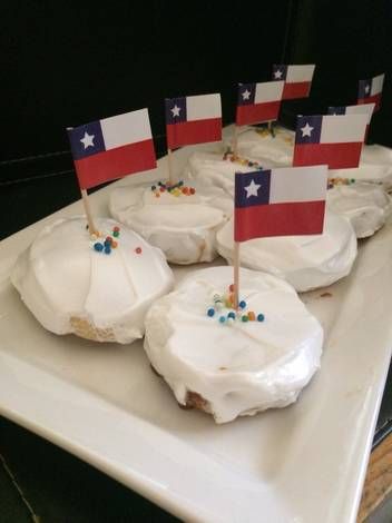 several cupcakes with flags on them sitting on a white platter, ready to be eaten