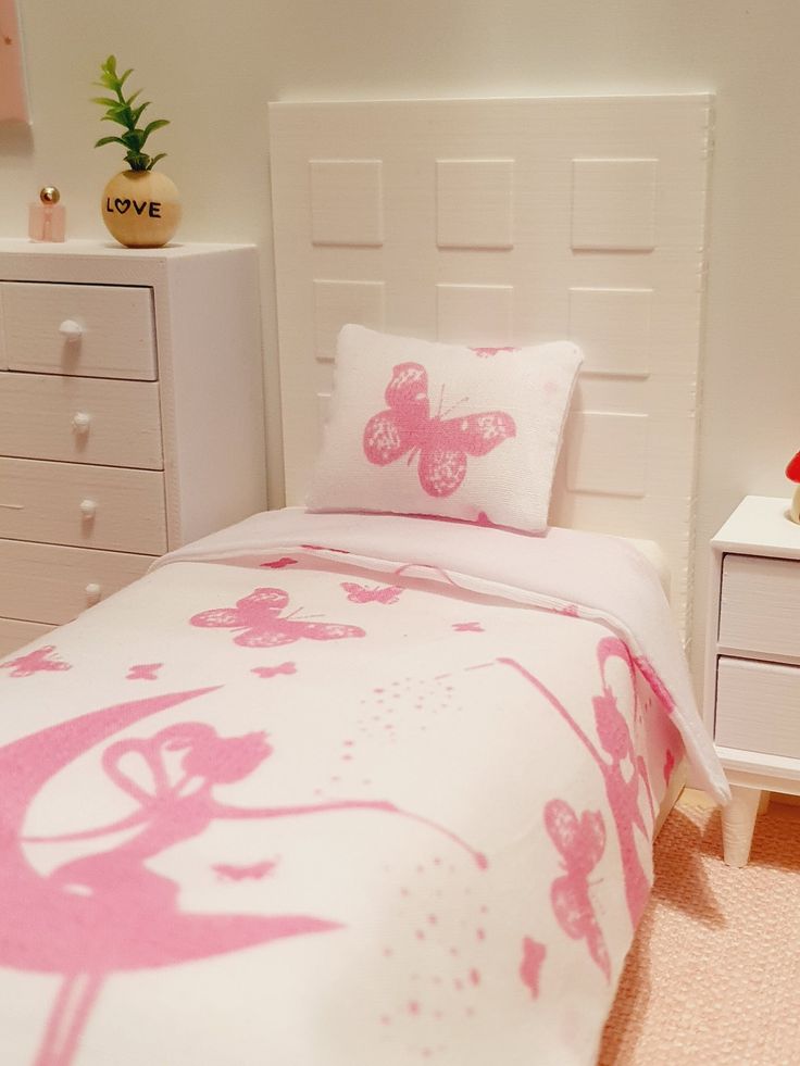 a white bed with pink butterflies on it in a room next to a dresser and drawers