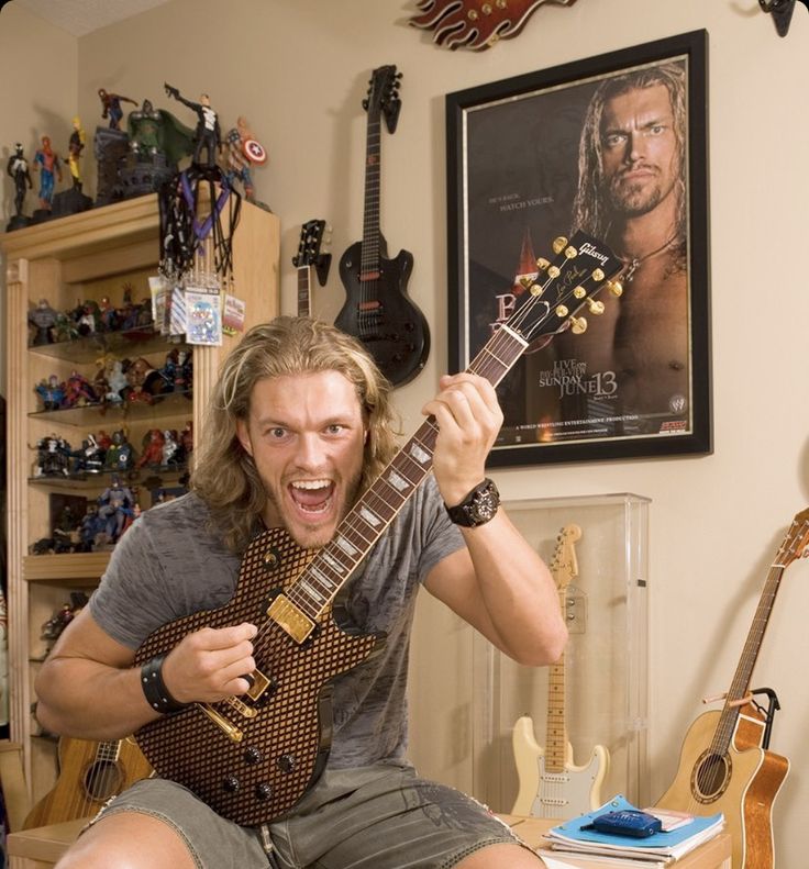 a man sitting on top of a chair holding a guitar in front of him with his mouth open