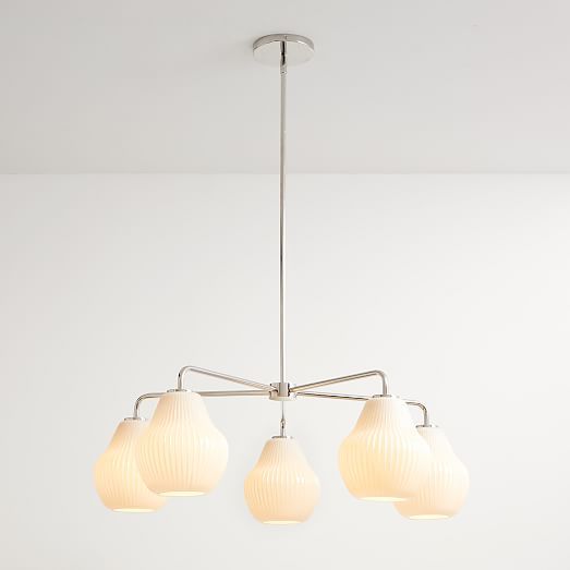 four light chandelier with white shades hanging from the ceiling in an empty room