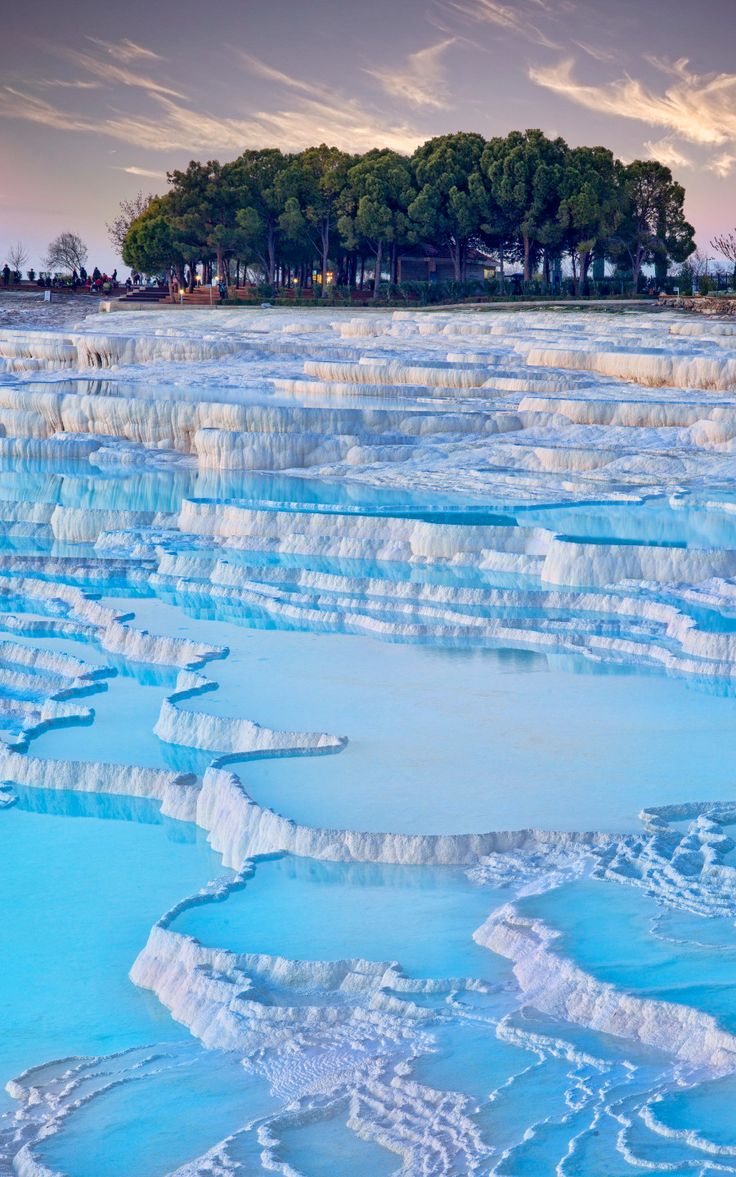 the water is very blue and there are some trees in the backgrouds