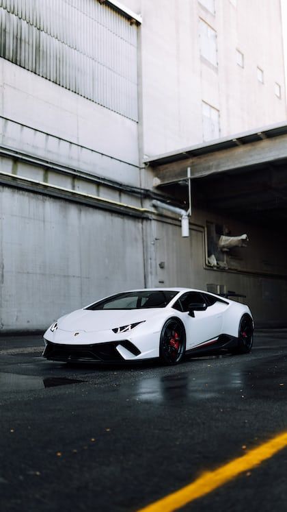 a white sports car parked in an empty parking lot next to a large concrete building