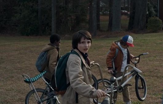 two boys with backpacks and bicycles in the park