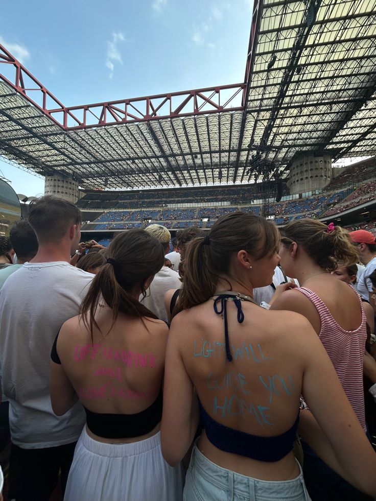 two women with tattoos on their back standing next to each other in front of an audience