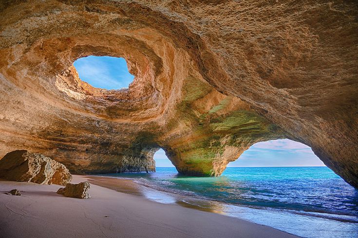 an image of the inside of a cave at the beach with water coming out from it