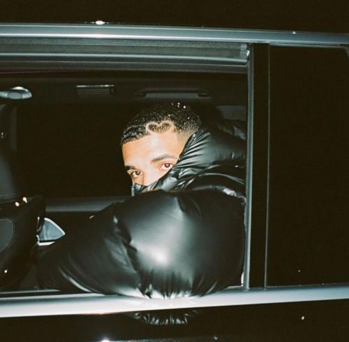 a man in black leather gloves leaning out the back door of a car at night