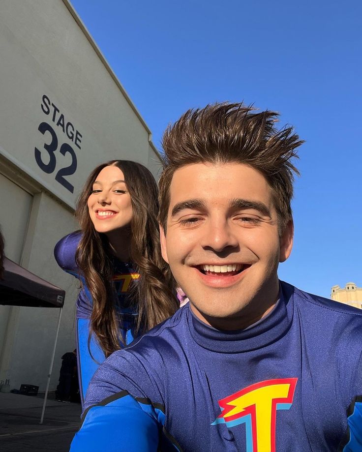 two young people are posing in front of a store with the number 32 on their shirt