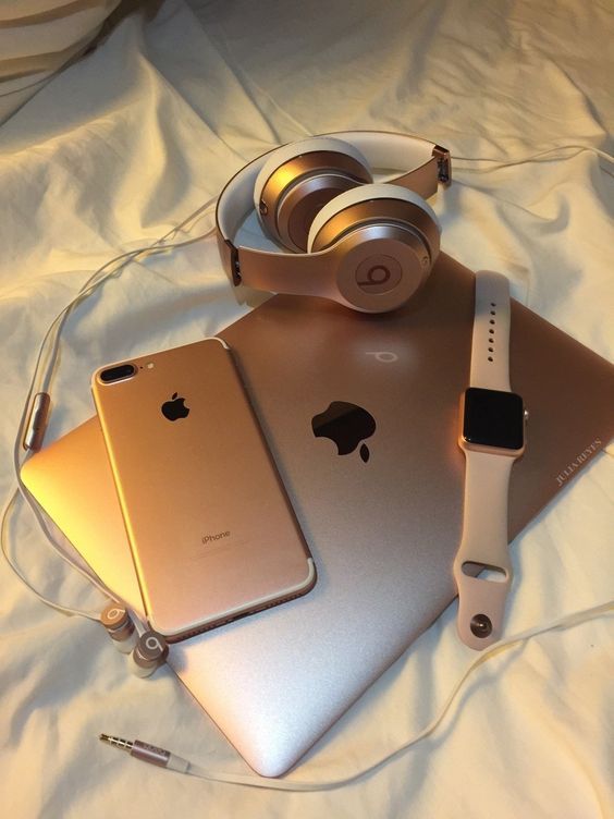 an apple laptop and headphones on top of a bed