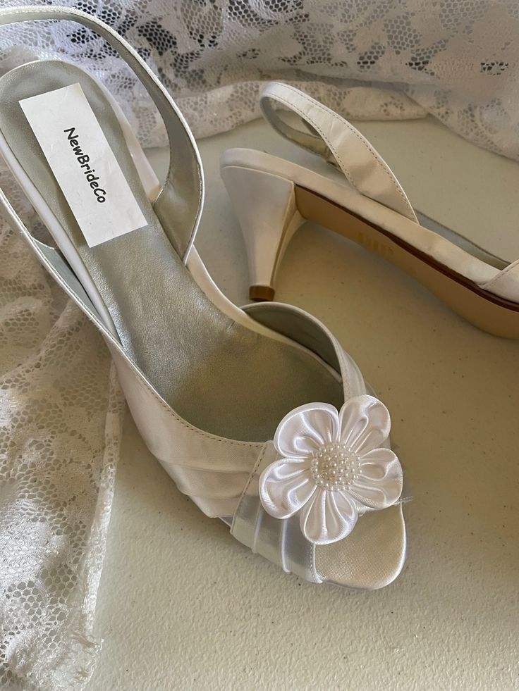 a pair of white shoes with a flower on the heel