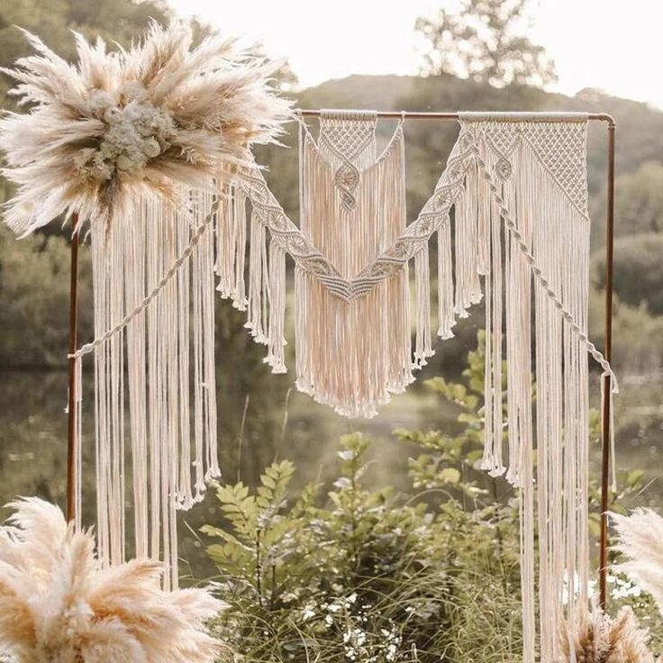 an outdoor wedding ceremony area with white flowers and macrame tassels hanging from the ceiling