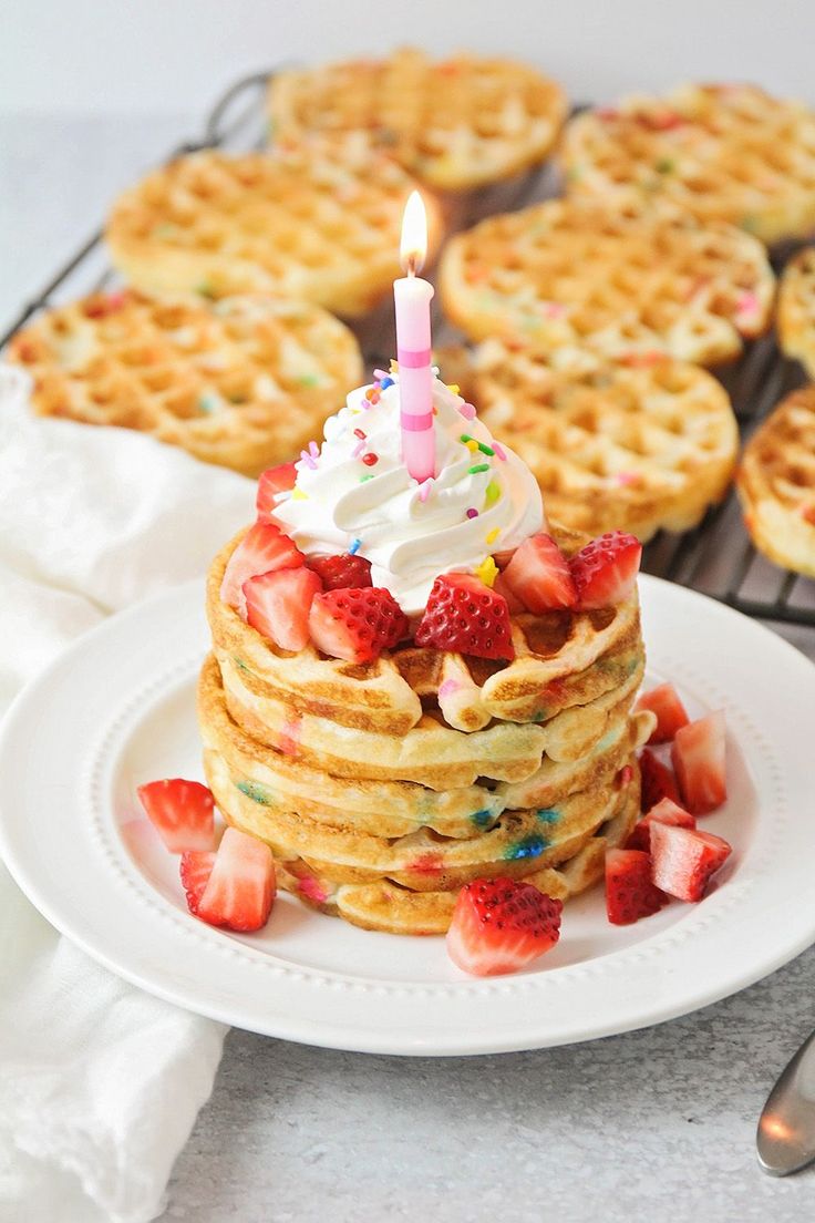 a stack of waffles with a birthday candle on top and strawberries in the middle