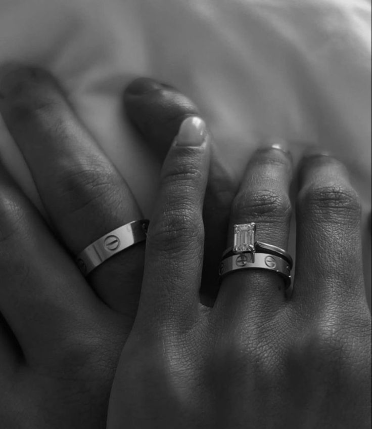 black and white photograph of two hands holding each other with wedding rings on their fingers