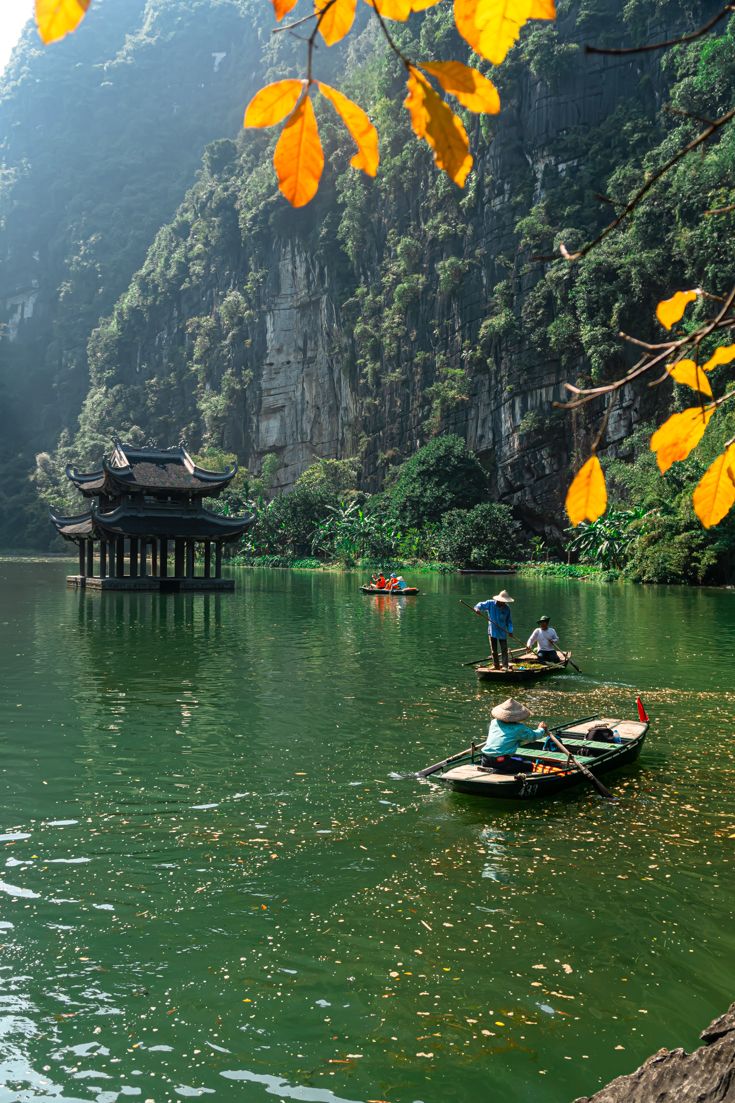 two small boats floating on top of a lake next to a forest covered mountain side
