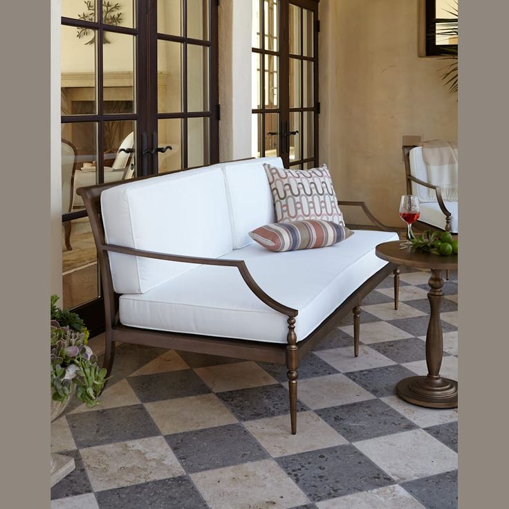 a white couch sitting on top of a checkered floor next to a glass door