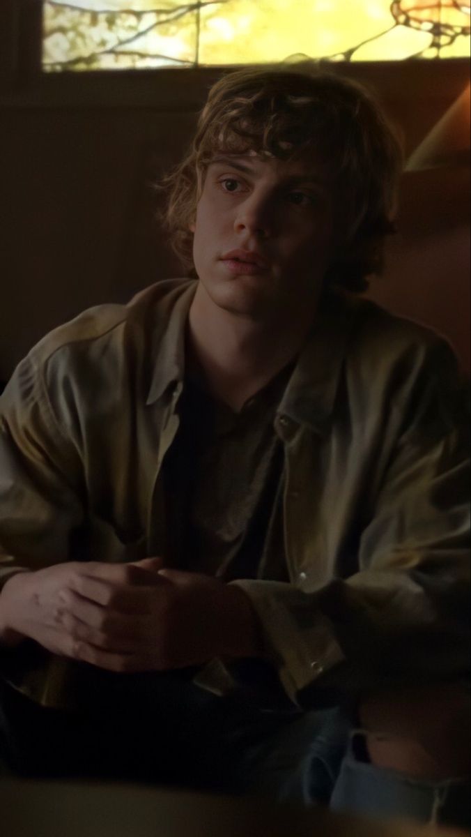 a young man sitting in front of a window