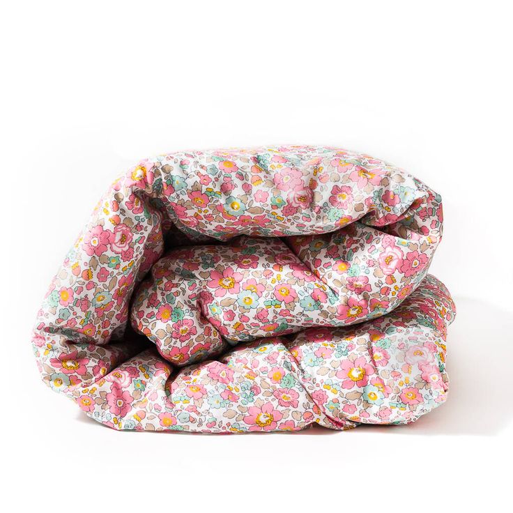 three pillows stacked on top of each other in front of a white background with flowers