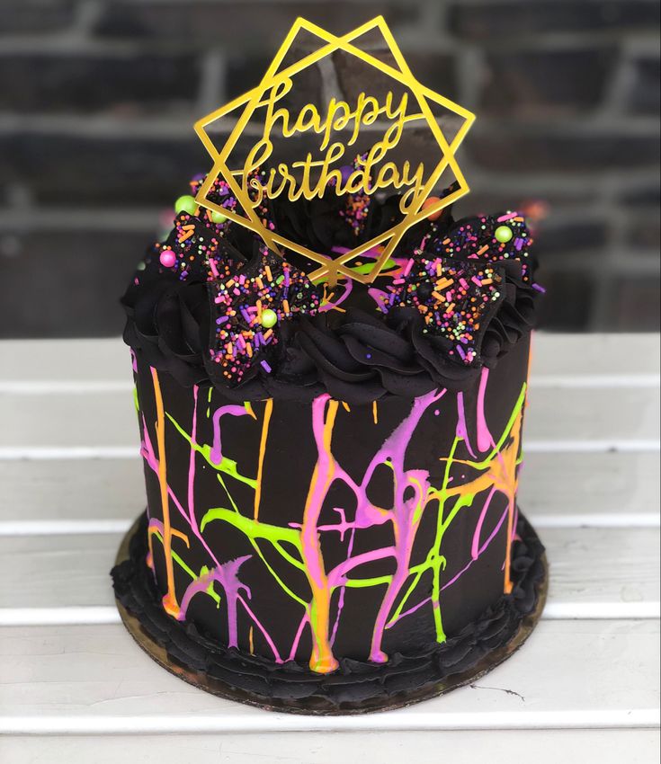 a birthday cake decorated with black icing and sprinkles