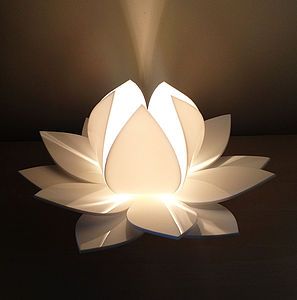 a large white flower shaped lamp sitting on top of a wooden table next to a wall