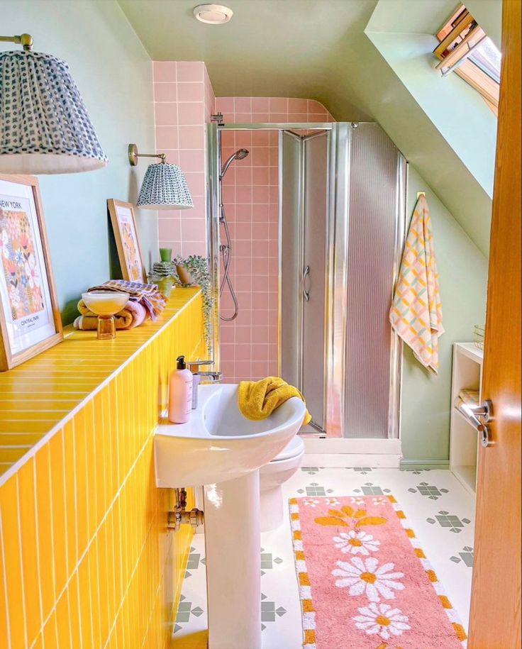 a bathroom with yellow and pink tiles on the floor, sink, shower stall and rug