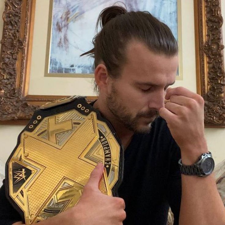 a man sitting on a couch with a wrestling belt in front of his face and finger to his nose