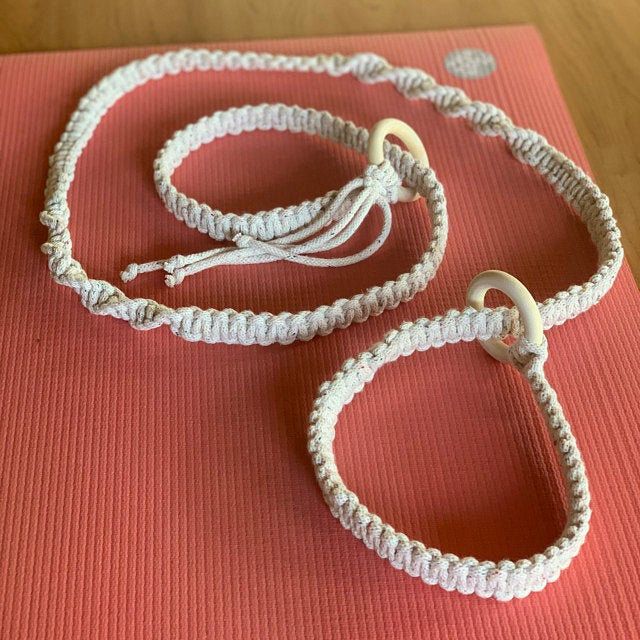 two white bracelets on top of a yoga mat with a silver hook in the middle
